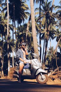 Man wearing sunglasses sitting on palm tree