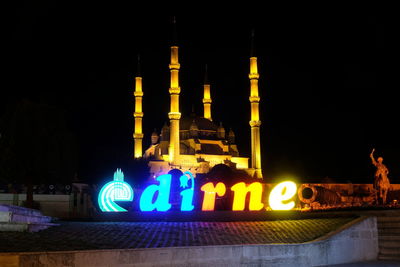 Low angle view of illuminated sign against sky at night