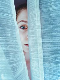 Portrait of young woman behind curtain