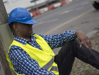 Side view of man sitting on street