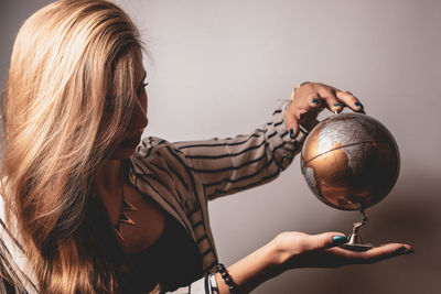 Woman looking at globe against gray background