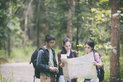 Friends using map in forest