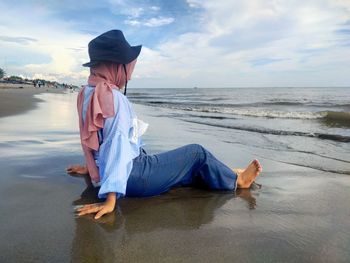 Full length of young woman on beach against sky