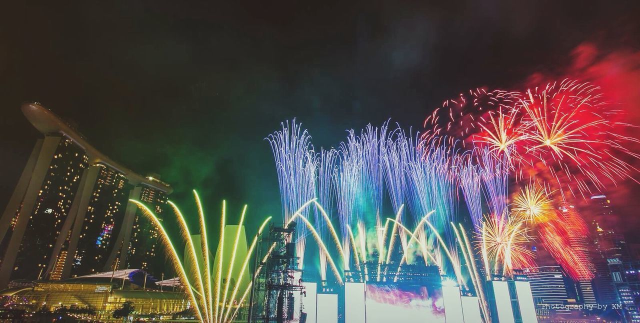 illuminated, night, celebration, firework display, long exposure, multi colored, exploding, arts culture and entertainment, firework - man made object, building exterior, motion, sky, built structure, low angle view, event, architecture, blurred motion, firework, city, celebration event