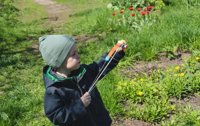 Child 4-year-old shoots up with a bow outside. side view.