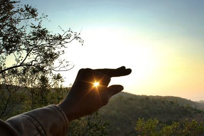 Close-up of hand holding sun at sunset