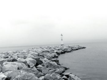 Lighthouse by sea against sky