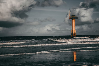 Lighthouse by sea against sky