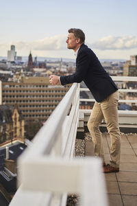 Thoughtful businessman leaning on terrace railing