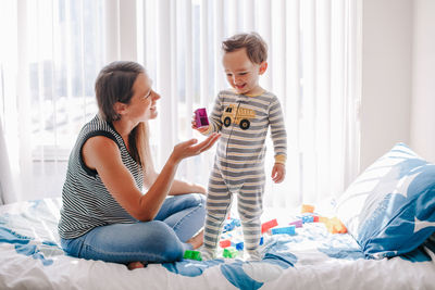 Mother and baby toddler playing building with learning toy stacking blocks at home. early age 