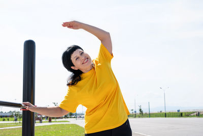 Young woman looking at camera against sky