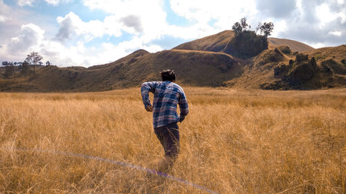 Rear view of man walking on field