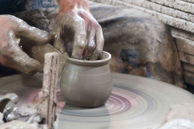 Midsection of potter making pot at workshop