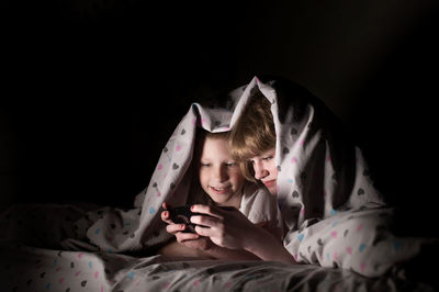 Lying under a blanket, hiding from parents, brother and sister