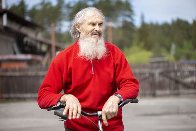 Old man with a gray beard resting on the handlebar of a bicycle