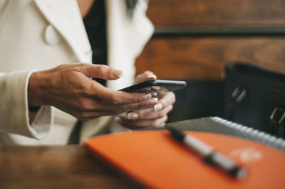 Midsection of man holding smart phone on table