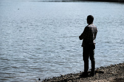 Rear view of man standing at beach