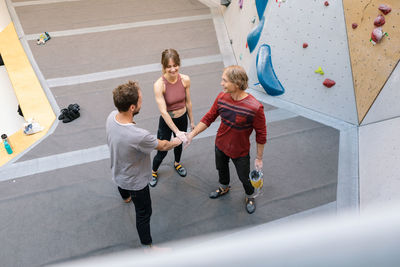 High angle view of coach and student stacking hands in unity at gym