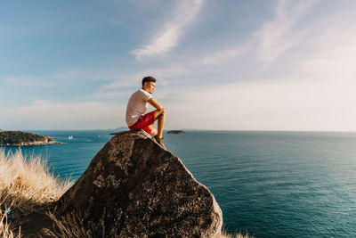 Man rest on the sea cliff rock after finish his hike trail.