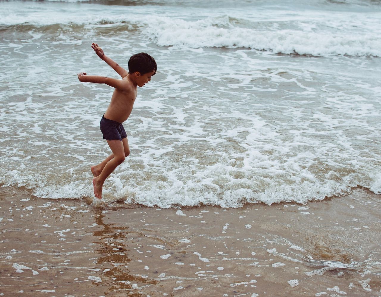 shirtless, sea, beach, childhood, boys, real people, full length, one person, leisure activity, wave, sand, elementary age, motion, lifestyles, fun, day, water, one boy only, vacations, playing, outdoors, nature, jumping, people