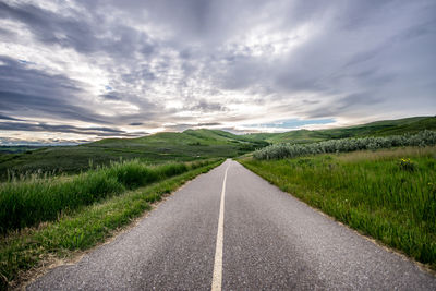 Road amidst green landscape against sky