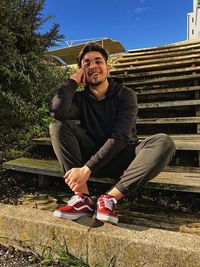 Portrait of smiling young man sitting at park