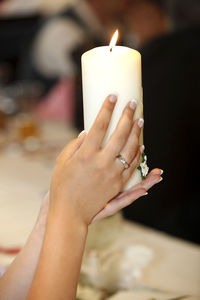 Cropped hand of woman holding lit candle