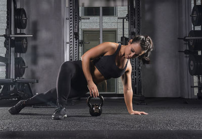 Young woman exercising with kettlebell at gym