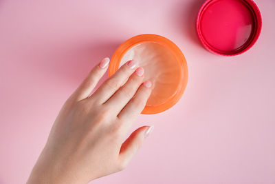 Female hands with a bottle of cream on a pink background. spa and body care concept. 