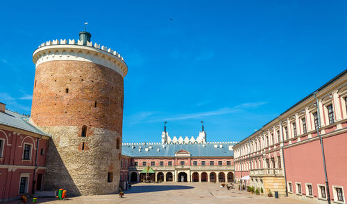 Tower amidst buildings against blue sky