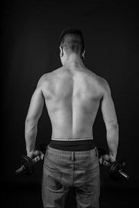 Full length of shirtless man standing against black background