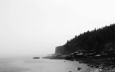 Scenic view of sea and rocks against clear sky