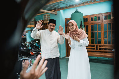 Man and woman waving guest at home