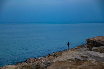 High angle view of man fishing in sea against sky