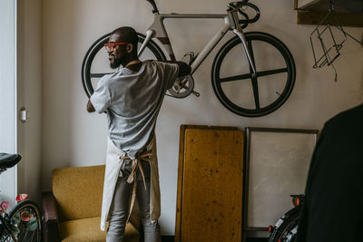 Rear view of male owner repairing bicycle in workshop