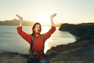 Woman standing at beach against sky during sunset