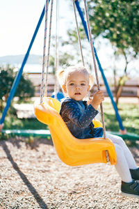 Portrait of boy swinging at playground