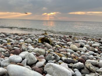 Rocks on beach against sky during sunset