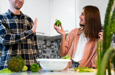 Portrait of smiling friends using mobile phone while sitting on table