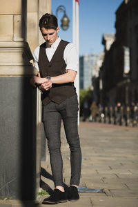 Fashionable man standing on footpath by building in city