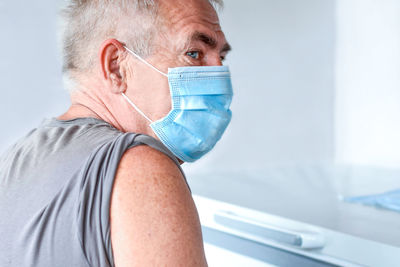 Elderly man in face mask getting covid vaccine. doctor giving injection to senior man at hospital