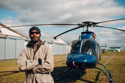 Portrait of man standing on motorcycle against sky