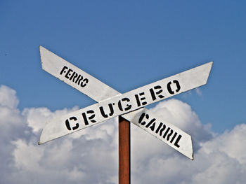 Low angle view of road sign against blue sky