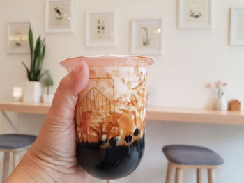 Midsection of woman holding milk tea at home