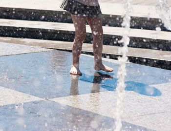 Low section of person walking by fountain on wet footpath