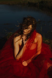 Midsection of woman sitting by red water