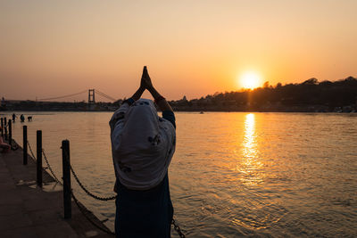 Young indian girl praying the holy ganges river and sun setting at horizon at river bank