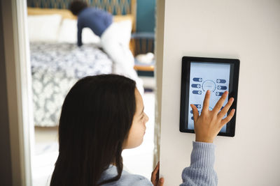Girl touching screen of home automation device on wall at home