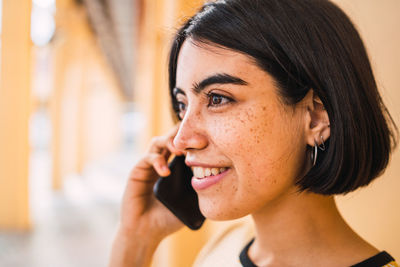 Close-up of smiling woman talking on smart phone standing outdoors