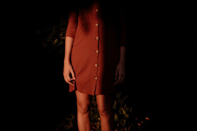 Midsection of woman standing against black background